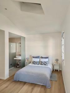 ein weißes Schlafzimmer mit einem großen Bett mit blauen Kissen in der Unterkunft Seven Funchal Apartments in Funchal