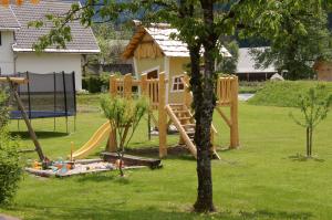 een houten speeltuin in een tuin met een boom bij Apartma Hkavc Markež in Bohinj