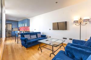 ein Wohnzimmer mit blauen Sofas und einem Tisch in der Unterkunft Alcazar Pool Villa by Valcambre in Sevilla
