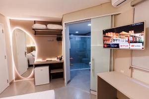a room with a bathroom with a tv and a bedroom at Tonello Business Hotel in Campo Mourão
