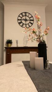 a vase with flowers in a room with a clock at Splendid Stays by Citybricks in Kent