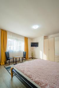 a bedroom with a bed and a table and yellow curtains at Hera's Garden in Arad