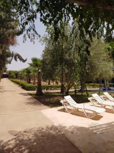a row of white lounge chairs in a park at la Paysanne by Souna in Marrakesh