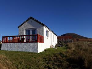 a white house with a red balcony on a hill at Garvault House in Kinbrace