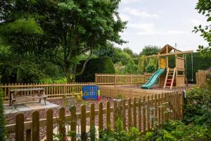 a playground with a wooden fence and a slide at Gardener's Cottage in Dorchester