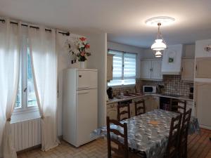 une cuisine avec une table et un réfrigérateur blanc dans l'établissement maison individuel proche des châteaux et Amboise avec jardin clos, à Pocé-sur-Cisse 13 autres photos