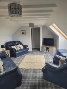 a living room with blue couches and a tv at Lindisfarne Bed & Breakfast in Stromness