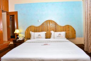 a bedroom with a large white bed with a wooden headboard at Breeze Hotel Nyahururu in Nyahururu