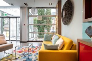 a living room with a yellow couch and a glass table at numa I Bona Rooms & Apartments in Bonn