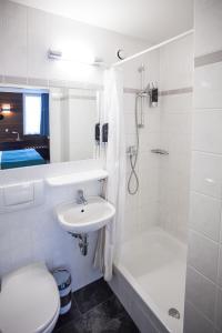 ein weißes Badezimmer mit einem Waschbecken, einem WC und einer Dusche in der Unterkunft Centro Hotel Ayun in Köln