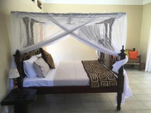a bedroom with a canopy bed with white curtains at C9 @ Diani Beachalets in Galu