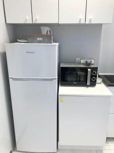 La cuisine est équipée d'un réfrigérateur blanc et d'un four micro-ondes. dans l'établissement Casa Cavaleri Sweet apartment MM Bande Nere, à Milan
