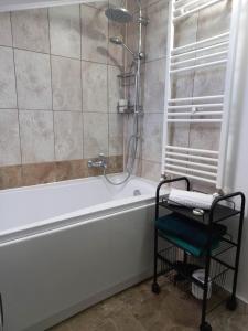 La salle de bains est pourvue d'une baignoire blanche et d'une douche. dans l'établissement Collot Residence Sibiu 2, à Turnişor