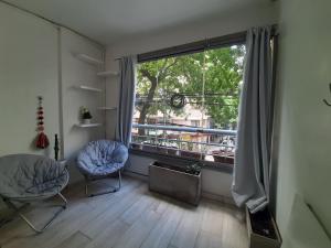 Habitación con 2 sillas y ventana grande. en Alto Palermo en Buenos Aires
