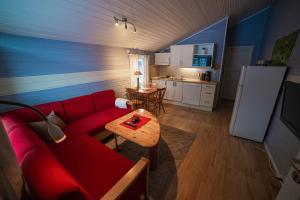 Førde Gjestehus og Camping في فورد: غرفة معيشة مع أريكة حمراء ومطبخ