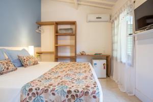 a bedroom with a bed with a comforter on it at Pousada Casalinda Camburi in Camburi