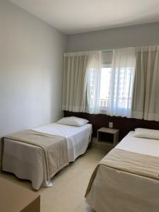 1 dormitorio con 2 camas y ventana en Apart Lagoaecotowers, en Caldas Novas