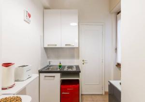 eine kleine Küche mit weißen Schränken und einer roten Schublade in der Unterkunft Navona Home in Rom