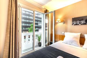 um quarto com uma cama e uma grande janela em Paris Expo Apart Hotel Porte de Versailles - Parking em Issy-les-Moulineaux