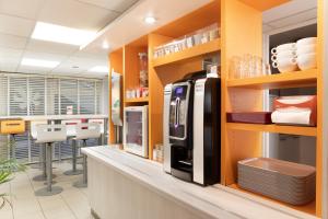 een keuken met een zwarte koelkast in een winkel bij Premiere Classe Fleury Merogis in Fleury-Mérogis