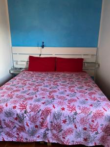1 cama con almohadas rojas y colcha rosa en Villa del Brigante, 200m from the beach, 80m², 2 bedrooms, 4-5 persons, en Capitana