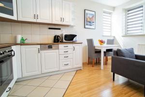 a kitchen with white cabinets and a table and a dining room at Warsaw Apartments - Apartamenty Wilanów in Warsaw