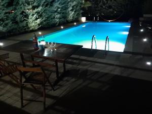 a table and chairs next to a swimming pool at night at Kantza Private Pool Project, near metro, A 60sm lux pool for your use only in Leondárion