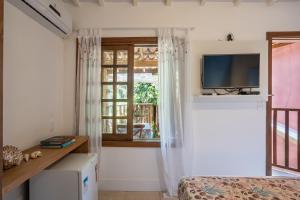 a bedroom with a tv and a window and a bed at Pousada Casalinda Camburi in Camburi
