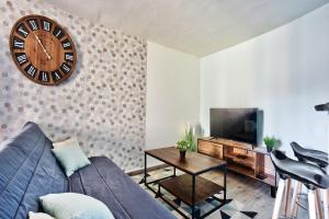 a living room with a couch and a clock on the wall at Appartement Le Spacieux Bressan - Hyper-Centre in Bourg-en-Bresse