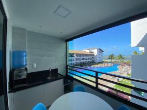 a room with a large window with a view of the beach at Lindo flat no Maui Beach Residence C201 in Tamandaré