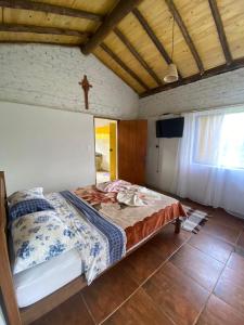 a bedroom with a bed with a cross on the wall at Chalé Boa Vista in Carrancas
