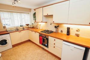 uma cozinha com armários brancos e um forno com placa de fogão em Cottages In Derbyshire - Apple Cottage em Belper