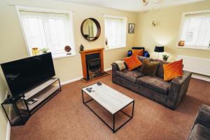 uma sala de estar com um sofá e uma televisão em Cottages In Derbyshire - Apple Cottage em Belper