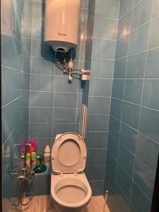 a bathroom with a toilet with a blue tiled wall at Сдам квартиры посуточно in Kokshetau