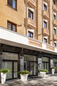 um edifício com vasos de plantas brancas à sua frente em BB Hotels Smarthotel Duomo em Milão