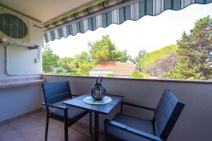 einen kleinen Tisch und Stühle auf einem Balkon mit Fenster in der Unterkunft Apartments Ela in Novalja