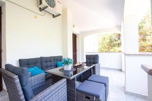 patio z wiklinowymi meblami, stołem i krzesłami w obiekcie Apartments Ela w Novalji