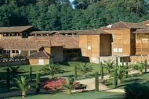 a large building with palm trees in front of it at Maison avec piscine proche des thermes in Mauléon-dʼArmagnac