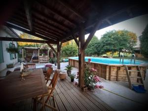 a wooden deck with a pool and a table and chairs at Maison avec piscine proche des thermes in Mauléon-dʼArmagnac