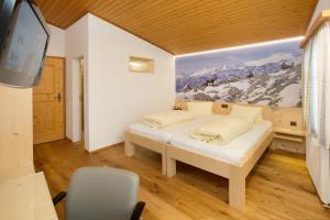 Hotel Alpsu في ديسنتس: غرفة نوم بسرير وتلفزيون وجدارية جبلية