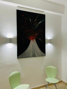 a painting hanging on a wall with two chairs at Roomors Of Naples - Sea View Apartment in Naples