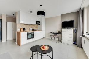 a kitchen and living room with a table and chairs at Comfort Apartments Morska in Gdynia