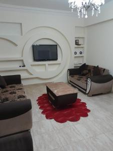 a living room with two couches and a flat screen tv at Charming 2-Bed Apartment in el zahabiazahabia in Hurghada