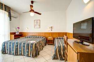 a bedroom with a bed and a flat screen tv at Hotel Genzianella in Cervia