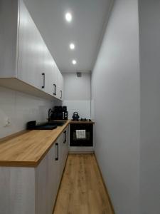 uma cozinha com armários brancos e piso em madeira em Apartament w Centrum em Jastrzebie-Zdrój