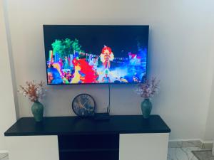 a tv hanging on a wall with two vases at Arabel Studio Apartment in Nanyuki