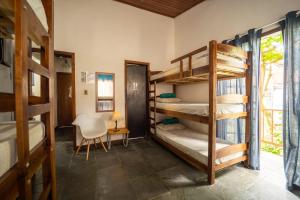 a room with bunk beds with a desk and a chair at Hostel Papagaio in Abraão
