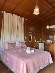 1 dormitorio con 1 cama grande con sábanas rosas en Pousada BANGALÔS SOL DE LAGOINHA, en Paraipaba