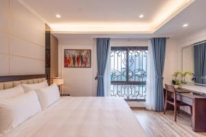 a bedroom with a bed and a desk and a window at Reyna Luxury Hotel in Hanoi