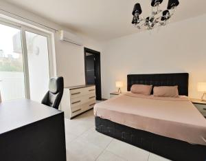 a bedroom with a bed and a chandelier at Large Central Apartment Near Valletta & Seafront in Pieta